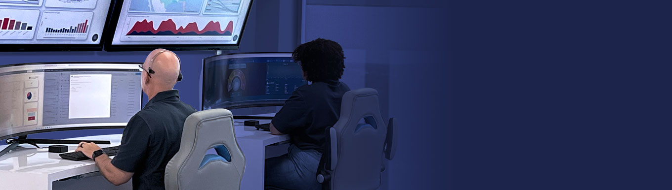 two cybersecurity analysts working in the security operations center (SOC) with dashboards displayed on large monitors