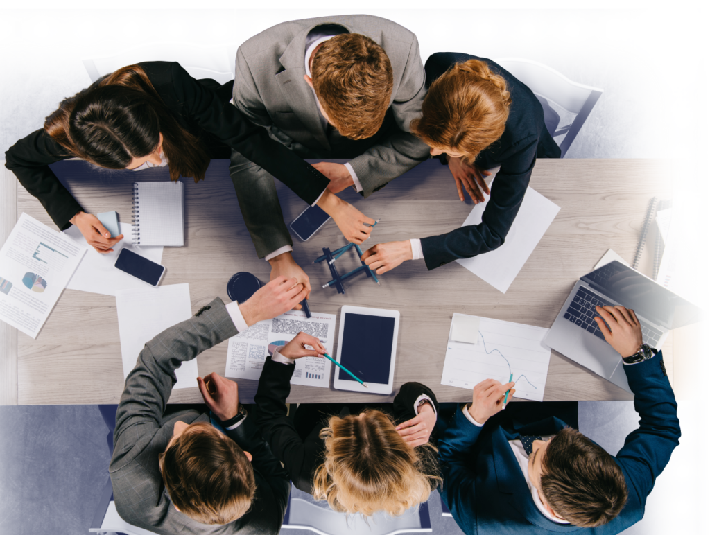 Overhead view of six business people sitting and working on tabletop exercises